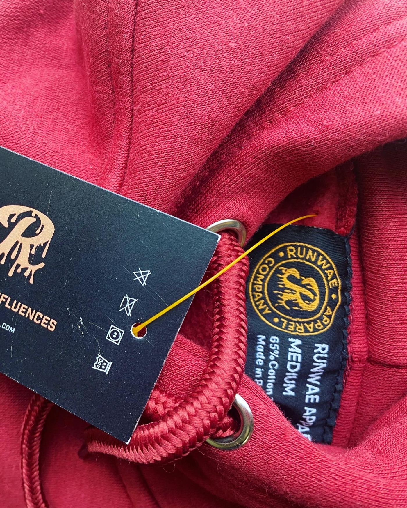 A red Runwae hoodie with its woven label and hang tag