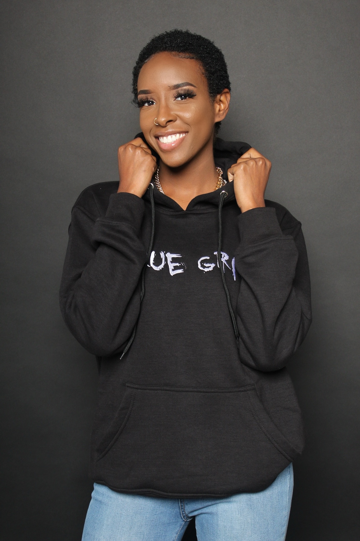 A woman in a black Runwae hoodie, studio portrait